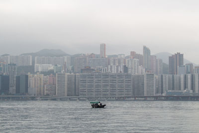 Boat in sea by buildings against sky in city