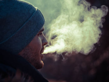 Side view of young man smoking cigarette