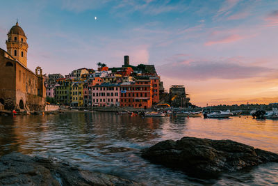 Buildings at waterfront during sunset