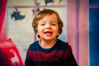 Closeup of an child with a happy face and blue eyes with a christmas background. merry christmas.