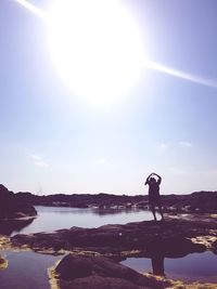 Man standing by lake against sky