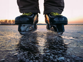 Low section of man ice skating against sky