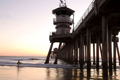 Silhouette pier on beach against sky during sunset