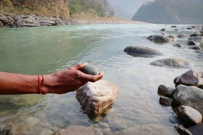 Close-up of hand holding rock in lake