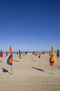 Group of people on beach against clear blue sky