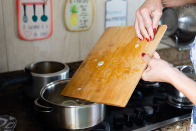 Young woman hands putting seasoning in pan for cooking.