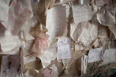 Close-up of papers with text stuck on wall