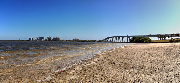 Arch bridge over sea against clear blue sky