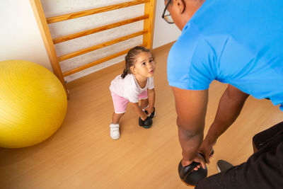 Little kid lifting kettlebell near father