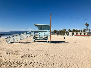 Lifeguard hut on beach against clear blue sky