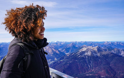 Side view of smiling young woman standing on mountain