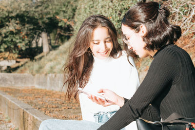 Smiling female friends looking at mobile phone