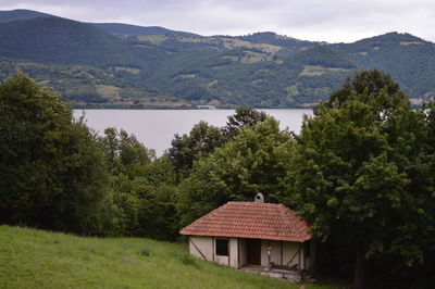 House and trees on mountain against sky