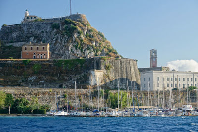 Buildings by sea against clear sky