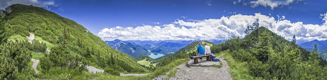 Panoramic view of people sitting on seat against mountains