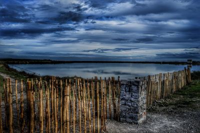 Wooden posts on beach against sky