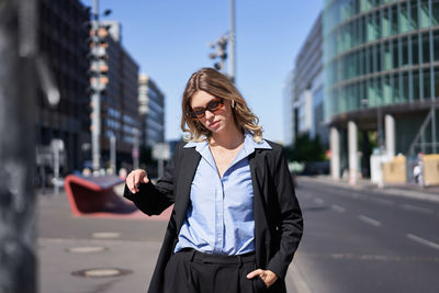 Young woman using mobile phone while standing in city