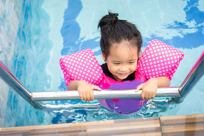 High angle view of girl smiling while swimming in pool