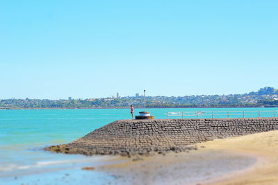 Boats in sea against clear blue sky