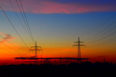 Silhouette electricity pylon against romantic sky at sunset