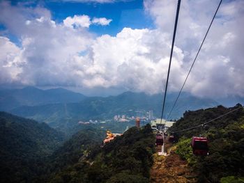 Overhead cable car over mountains against sky