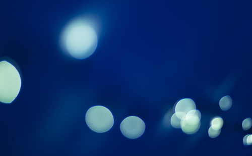 Low angle view of illuminated lights against clear blue sky