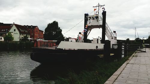 Boat in river by buildings against sky