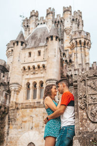 Low angle view of couple standing against historic building