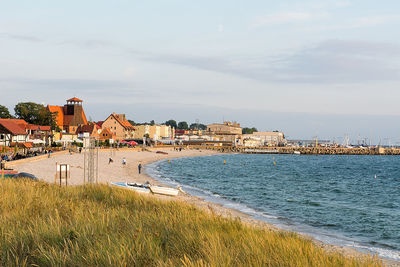 Buildings by sea against sky