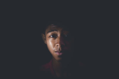 Close-up portrait of a serious young woman over black background