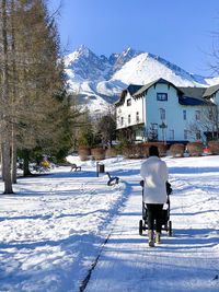 Woman in warm white teddy coat and hat pushing stroller in a snow covered mountain town