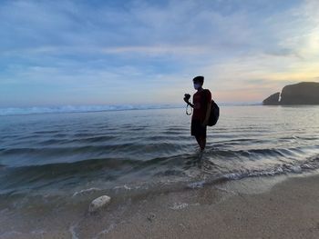 Full length of man standing on beach against sky