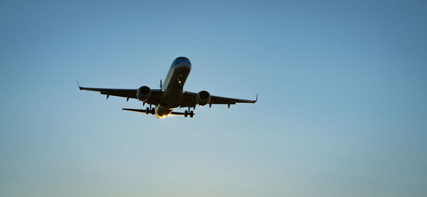 Low angle view of airplane against clear blue sky
