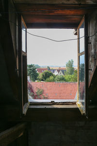 Houses against sky seen through window of house