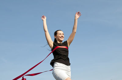 Low angle view of smiling mid adult racer crossing finishing line