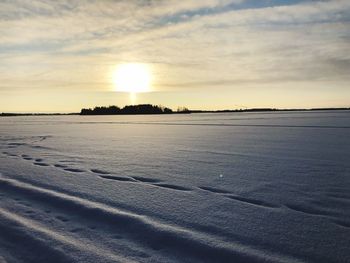 Scenic view of snowy field against sky during sunset