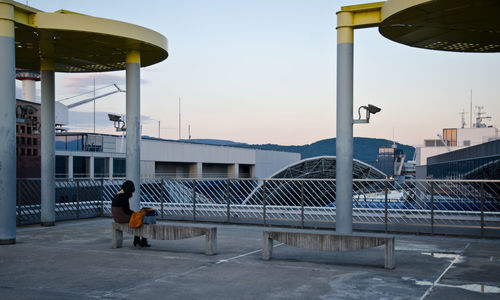 Rear view of man standing by railing against sky