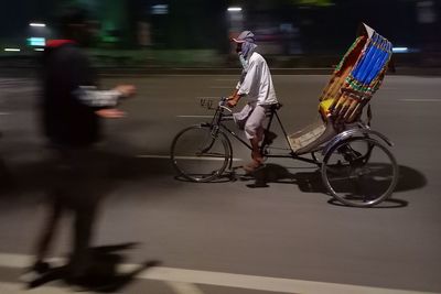 Panning rear view of man riding rickshow on street