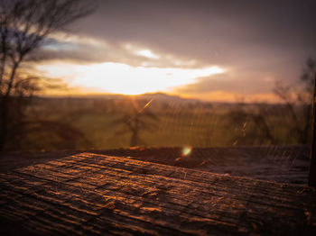 Close-up of wood on field against sky during sunset