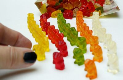 Cropped image of woman picking up gummi bear at table