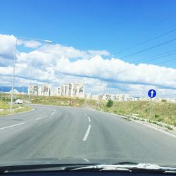 Road passing through highway against cloudy sky