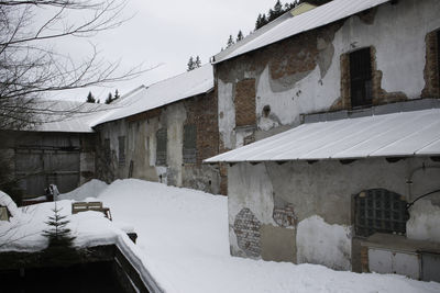 Snow covered houses by buildings against sky