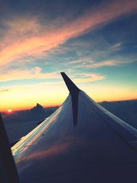 Close-up of airplane wing against sky during sunset