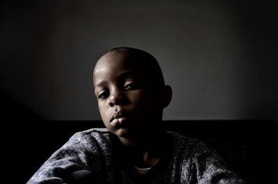 Portrait of boy sitting at home against wall