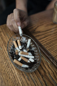 Close-up of hand holding cigarette on table