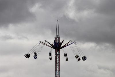 Low angle view of people in chain swing ride against sky
