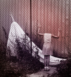 Digital composite image of girl standing against chainlink fence