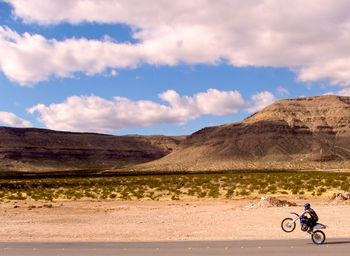 Man with umbrella on desert against sky