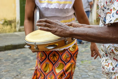 Tambourine player with a woman in typical clothes in the background in pelourinho, salvador, bahia