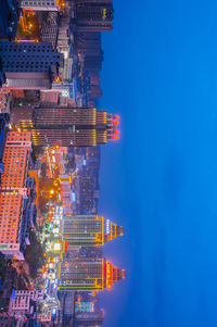 Illuminated cityscape against blue sky